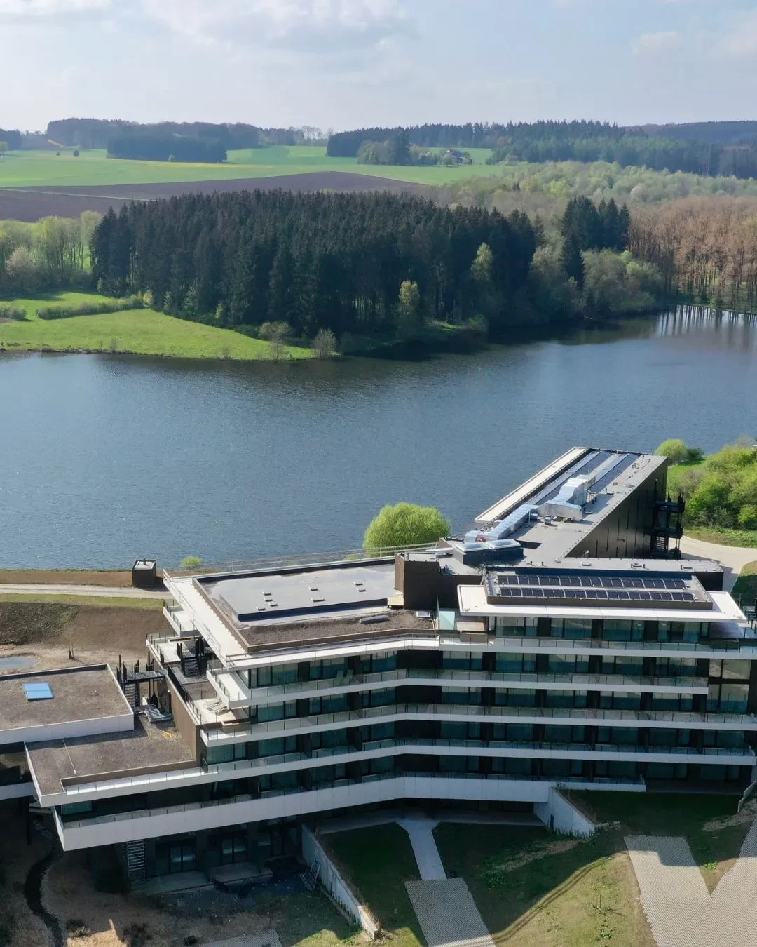Bâtiment moderne près d'un lac entouré de forêt.