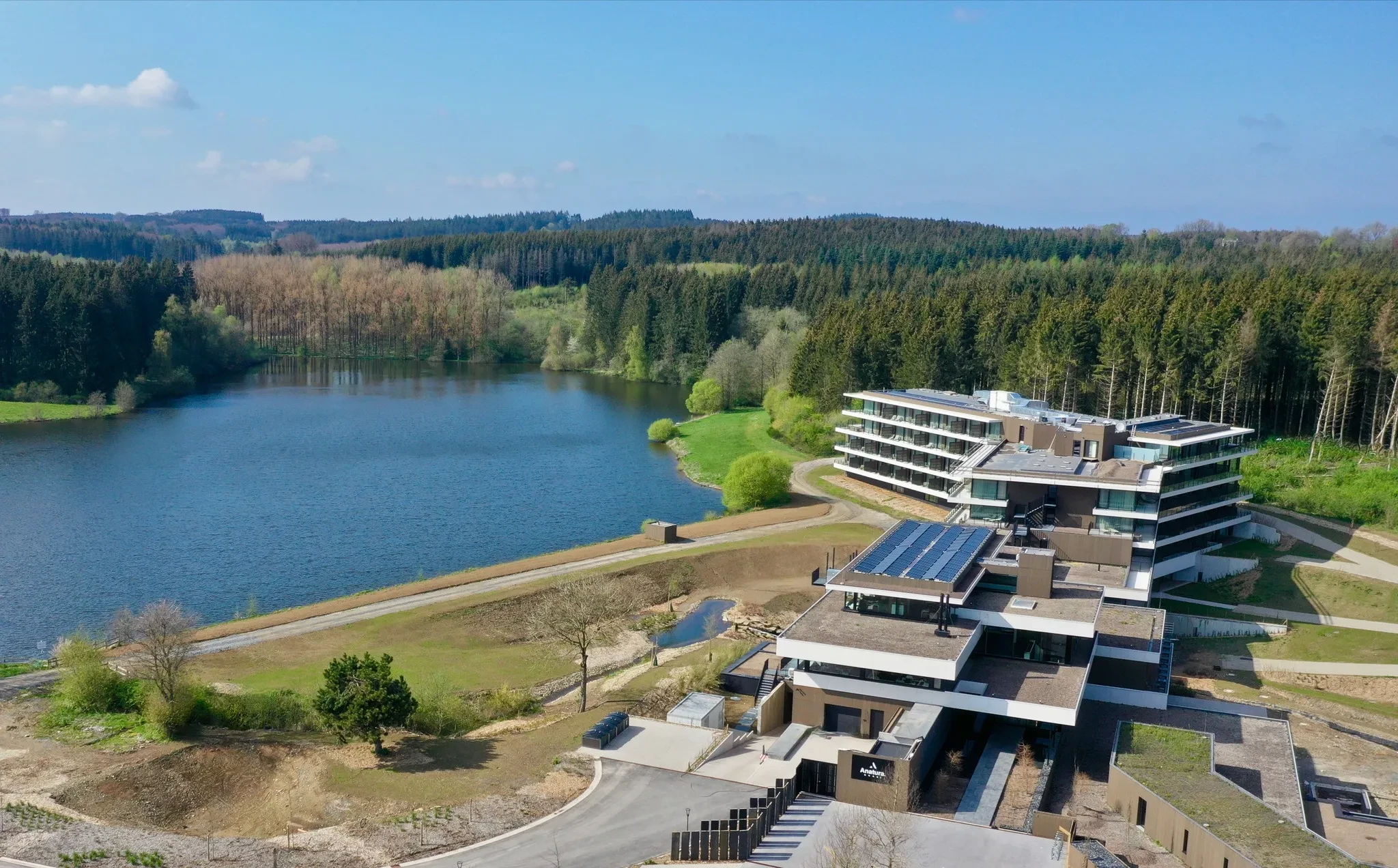 Complexe moderne près d'un lac et forêt.