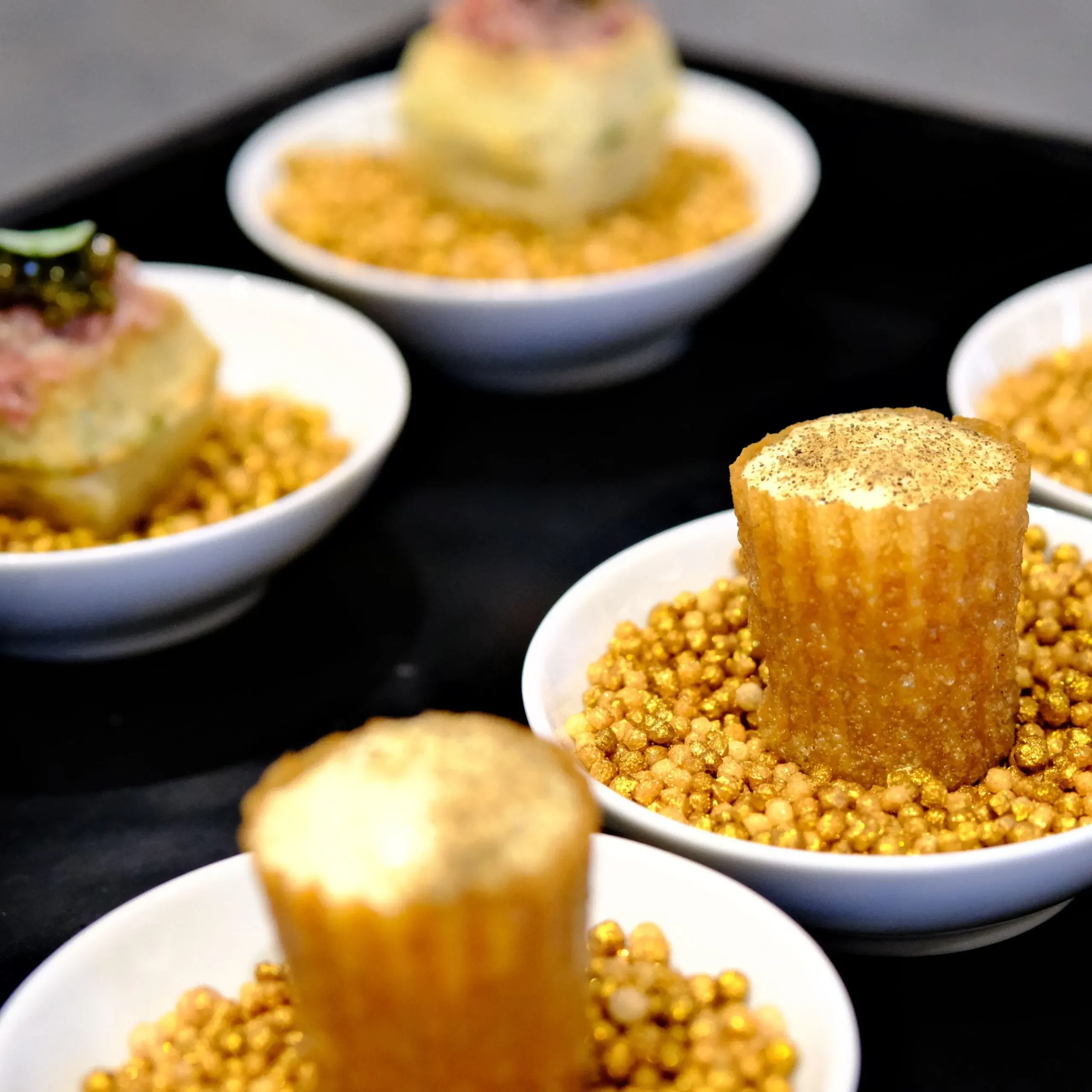 Desserts gourmands sur lit de perles dorées.
