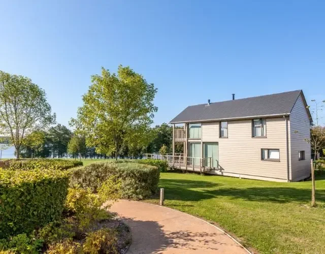 Maison moderne avec jardin et vue sur lac.